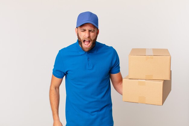 Young handsome man shouting aggressively, looking very angry. package delivering concept