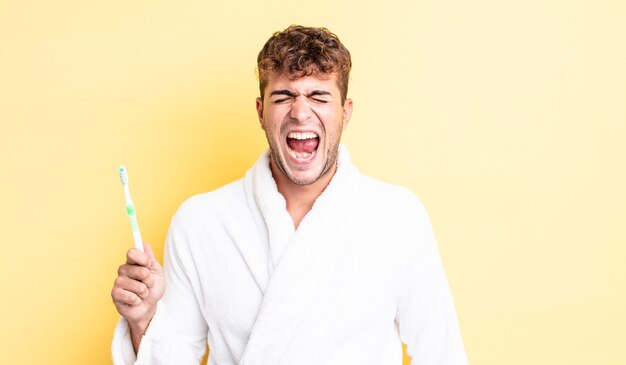 Young handsome man shouting aggressively, looking very angry. toothbrush concept