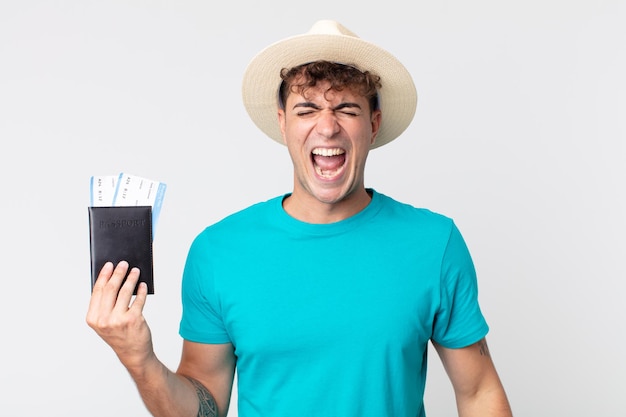 Young handsome man shouting aggressively, looking very angry. traveler holding his passport