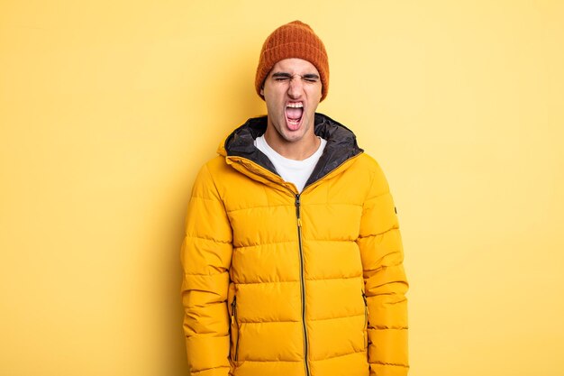 Young handsome man shouting aggressively, looking very angry. winter concept