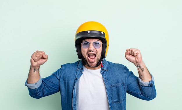 Young handsome man shouting aggressively with an angry expression. motorbike helmet concept