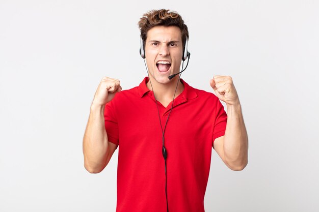 Foto giovane uomo bello che grida in modo aggressivo con un'espressione arrabbiata. concetto di telemarketing