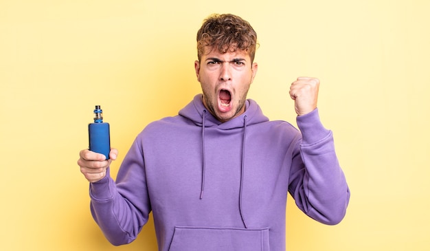 Young handsome man shouting aggressively with an angry expression. vaporizer concept