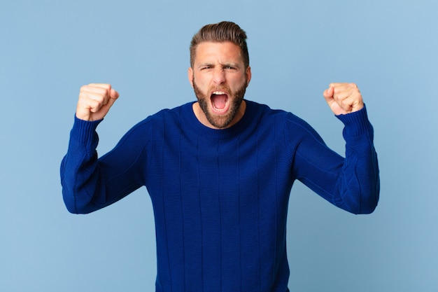 Young handsome man shouting aggressively with an angry expression