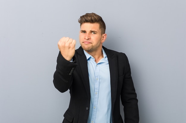 Young handsome man showing fist to camera, aggressive facial expression