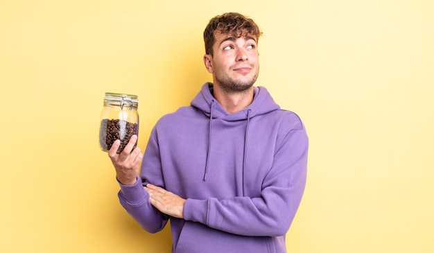 Young handsome man shrugging, feeling confused and uncertain. coffee beans concept