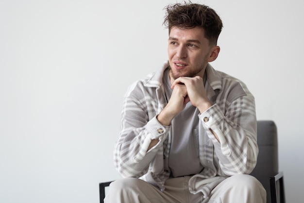 A young handsome man sitting on chairand posing isolated on white background