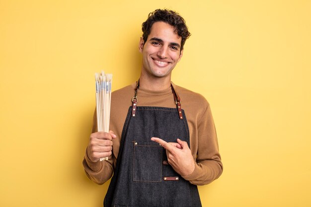 Young handsome man smiling cheerfully, feeling happy and pointing to the side. artist concept