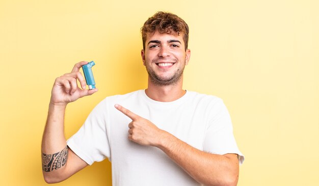 Young handsome man smiling cheerfully, feeling happy and pointing to the side. asthma concept