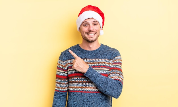 Young handsome man smiling cheerfully, feeling happy and pointing to the side. christmas concept