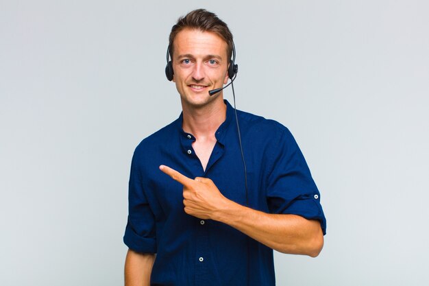 Young handsome man smiling cheerfully, feeling happy and pointing to the side and upwards, showing object in copy space