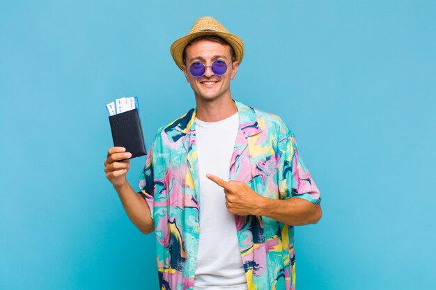 Young handsome man smiling cheerfully, feeling happy and pointing to the side and upwards, showing object in copy space