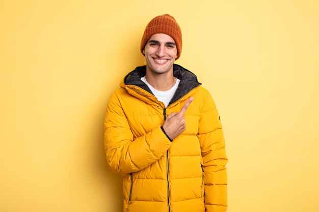 Young handsome man smiling cheerfully, feeling happy and pointing to the side. winter concept