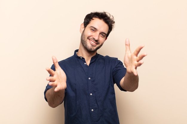 Young handsome man smiling cheerfully giving a warm, friendly, loving welcome hug