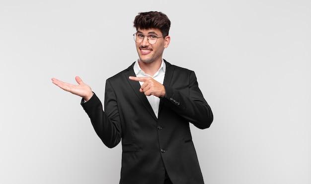 Young handsome man smiling cheerfully and pointing to copy space on palm on the side, showing or advertising an object