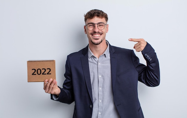 Giovane uomo bello che sorride con sicurezza indicando il proprio ampio sorriso. concetto di calendario