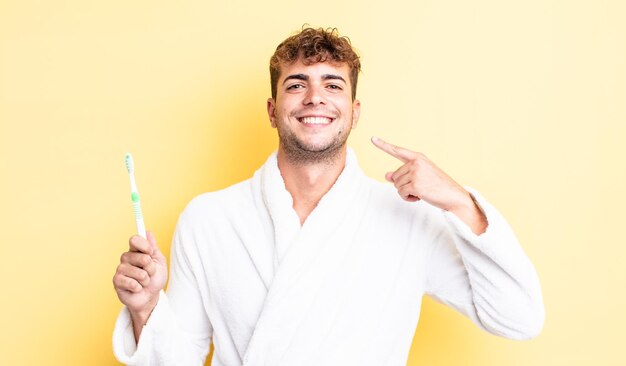 Young handsome man smiling confidently pointing to own broad smile. toothbrush concept