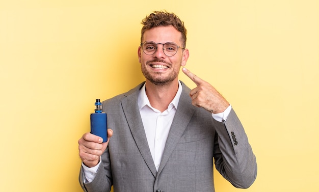 Young handsome man smiling confidently pointing to own broad smile. vaporizer concept