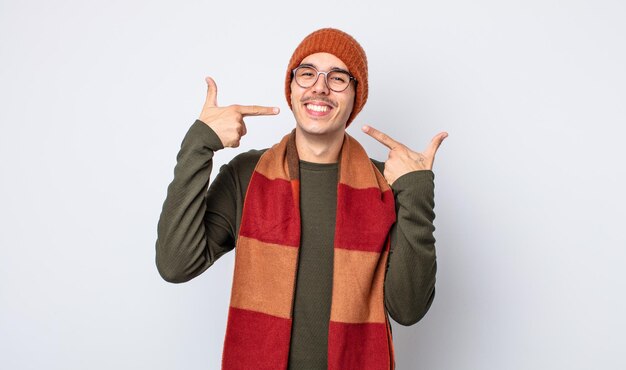 Young handsome man smiling confidently pointing to own broad smile. winter clothes concept