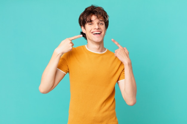 Young handsome man smiling confidently pointing to own broad smile