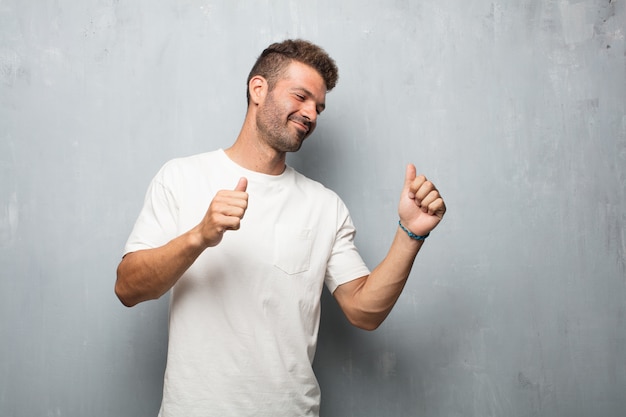 Young handsome man smiling and dancing to fun