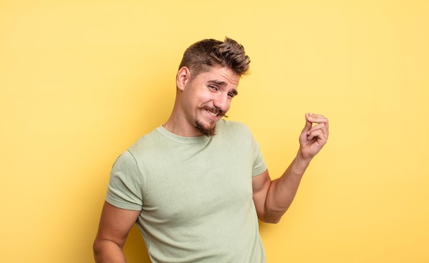 Young handsome man smiling, feeling carefree, relaxed and happy, dancing and listening to music, having fun at a party. strange moustache concept