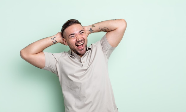 Young handsome man smiling and feeling relaxed, satisfied and carefree, laughing positively and chilling