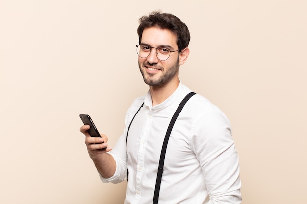 Young handsome man smiling to front with crossed arms and a happy, confident, satisfied expression, lateral view