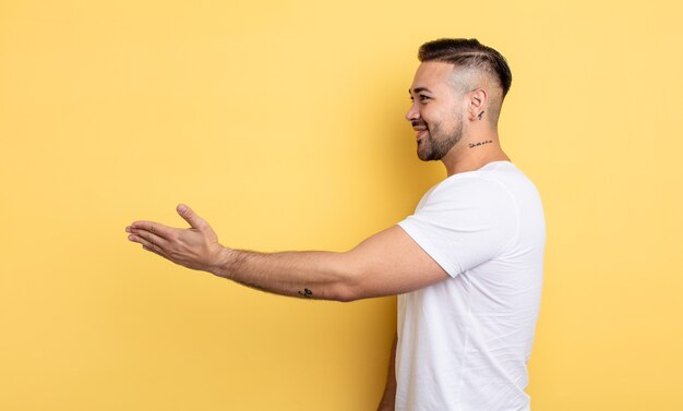 Foto giovane bell'uomo che sorride, ti saluta e ti offre una stretta di mano per concludere un affare di successo, concetto di cooperazione