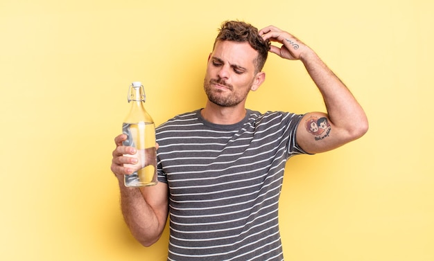 Young handsome man smiling happily and daydreaming or doubting. water concept