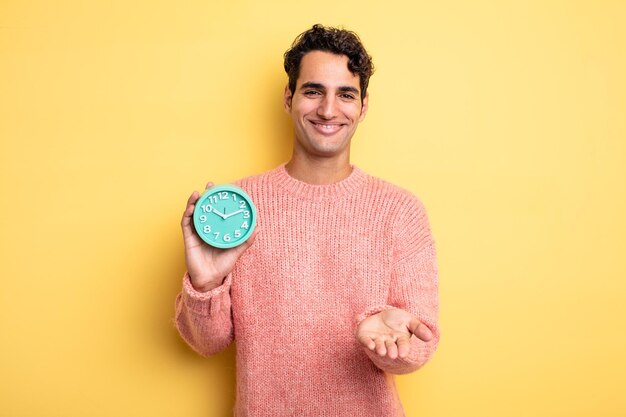 Young handsome man smiling happily with friendly and  offering and showing a concept alarm clock concept