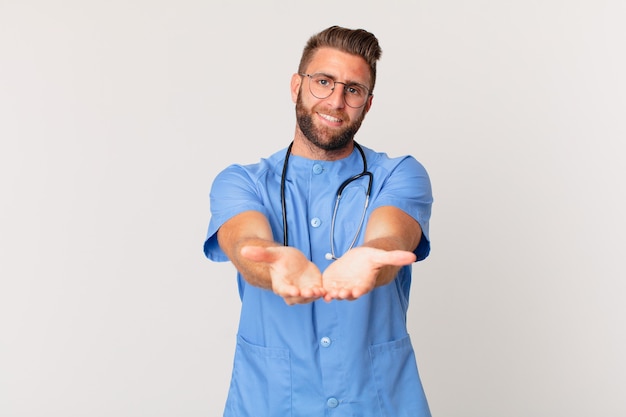 Foto giovane uomo bello che sorride felicemente con amichevole e offrendo e mostrando un concetto. concetto di infermiera