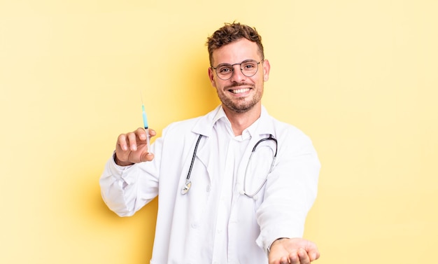 Photo young handsome man smiling happily with friendly and  offering and showing a concept. physician syringe concept