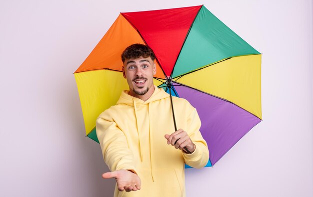 Young handsome man smiling happily with friendly and  offering and showing a concept. umbrella concept