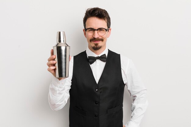 Young handsome man smiling happily with a hand on hip and confident cocktail bartender