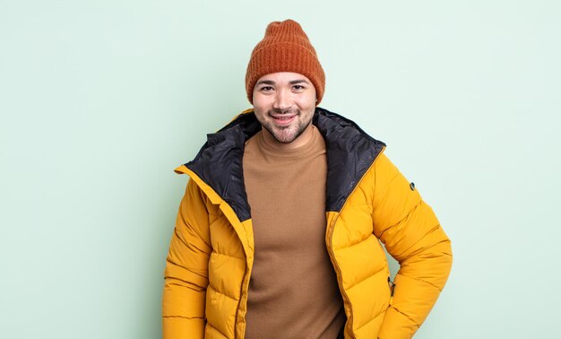 Giovane uomo bello che sorride felicemente con una mano sull'anca e fiducioso. concetto di tempo freddo