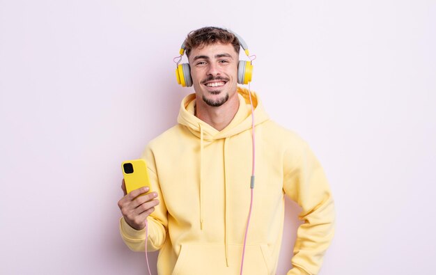 Young handsome man smiling happily with a hand on hip and confident. music concept