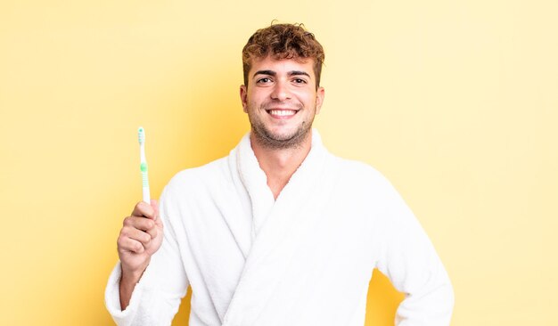 Young handsome man smiling happily with a hand on hip and confident. toothbrush concept