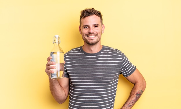 Young handsome man smiling happily with a hand on hip and confident. water concept