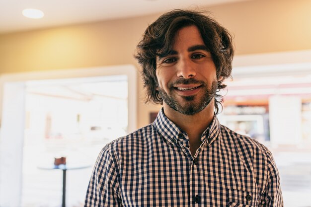 Young handsome man smiling indoor wearing a shirt.