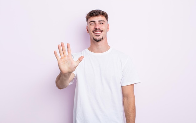 Young handsome man smiling and looking friendly, showing number five or fifth with hand forward, counting down