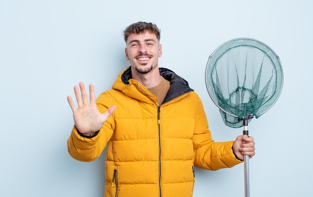 Young handsome man smiling and looking friendly, showing number five. fisherman concept