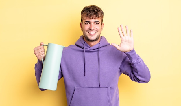 Young handsome man smiling and looking friendly, showing number five. thermos concept