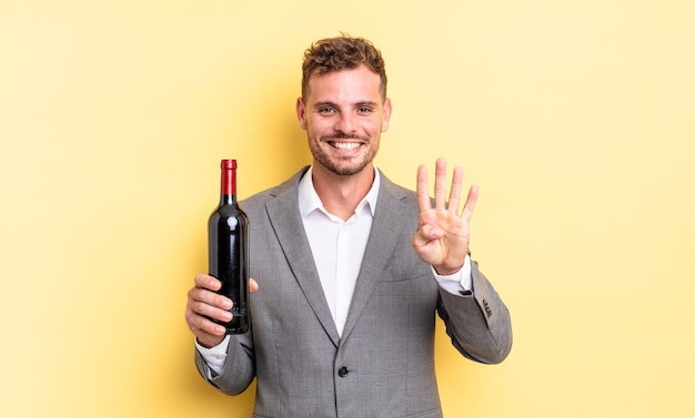 若いハンサムな男は笑顔でフレンドリーに見え、4番を示しています。ワインのコンセプトのボトル