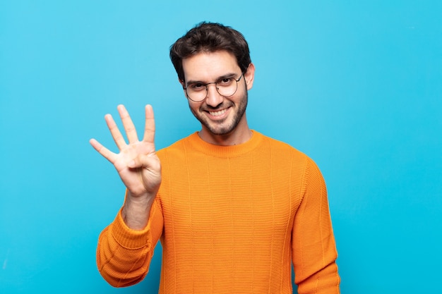 Young handsome man smiling and looking friendly, showing number four or fourth with hand forward, counting down