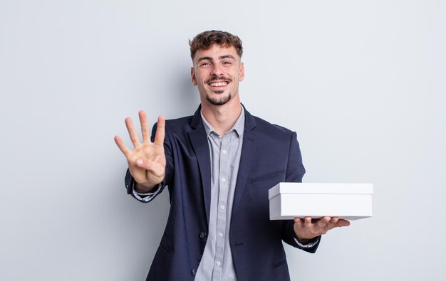 Young handsome man smiling and looking friendly, showing number four. white box package