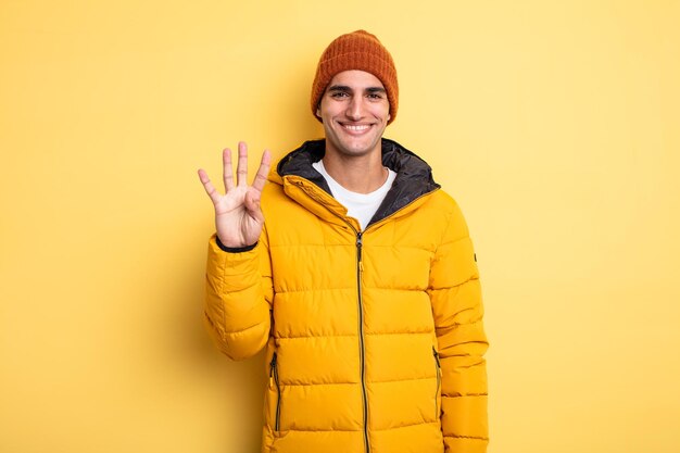 Young handsome man smiling and looking friendly, showing number four. winter concept