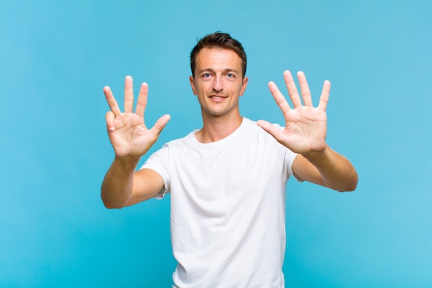 Young handsome man smiling and looking friendly, showing number nine or ninth with hand forward, counting down