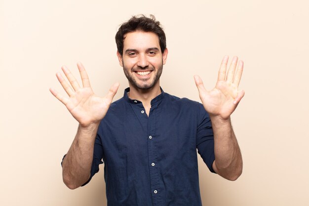 Young handsome man smiling and looking friendly, showing number nine or ninth with hand forward, counting down