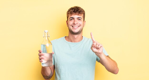 Young handsome man smiling and looking friendly, showing number one. water concept